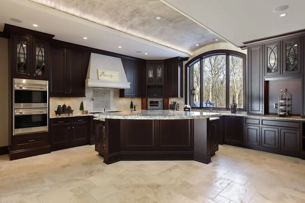 Espresso traditional kitchen with double wall ovens, a plaster range hood, granite island and travertine floor